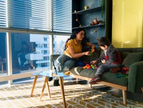 Niñera juega con un niño en el sofá de un apartamento