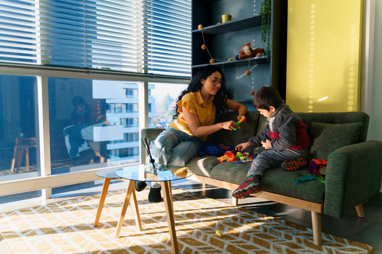 Niñera juega con un niño en el sofá de un apartamento